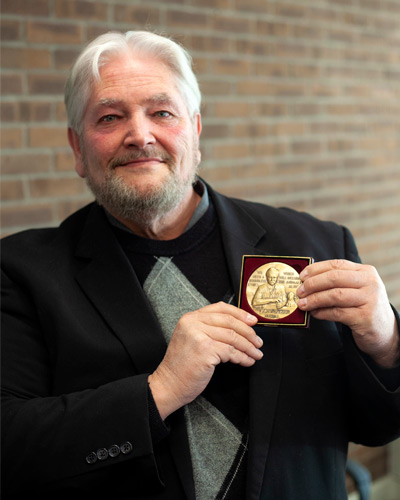 John Thompson holding Schweitzer Medal