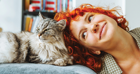 Teen girl and cat happily snuggle each other.