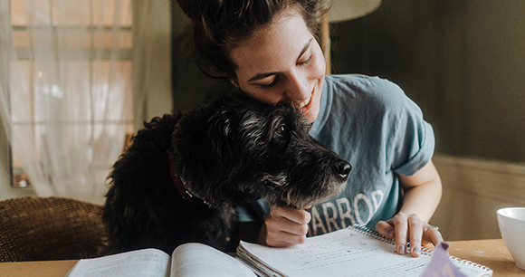 woman cuddling with dog while writing a paper woman cuddling with dog while writing a paper