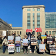 Advocates rally outside the Department of the Interior holding posters.