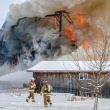 Firefighters battle a large winter barn fire using hoses.